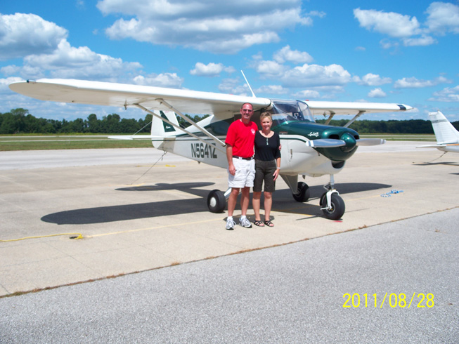 Steve & Rhonda, at Madison airport, in front of their air plane, wide camera shot.
